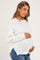 woman wearing a white knitted maternity sweater and holding her baby bump