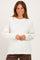woman wearing a cream knitted sweater with a relaxed fit and long sleeves