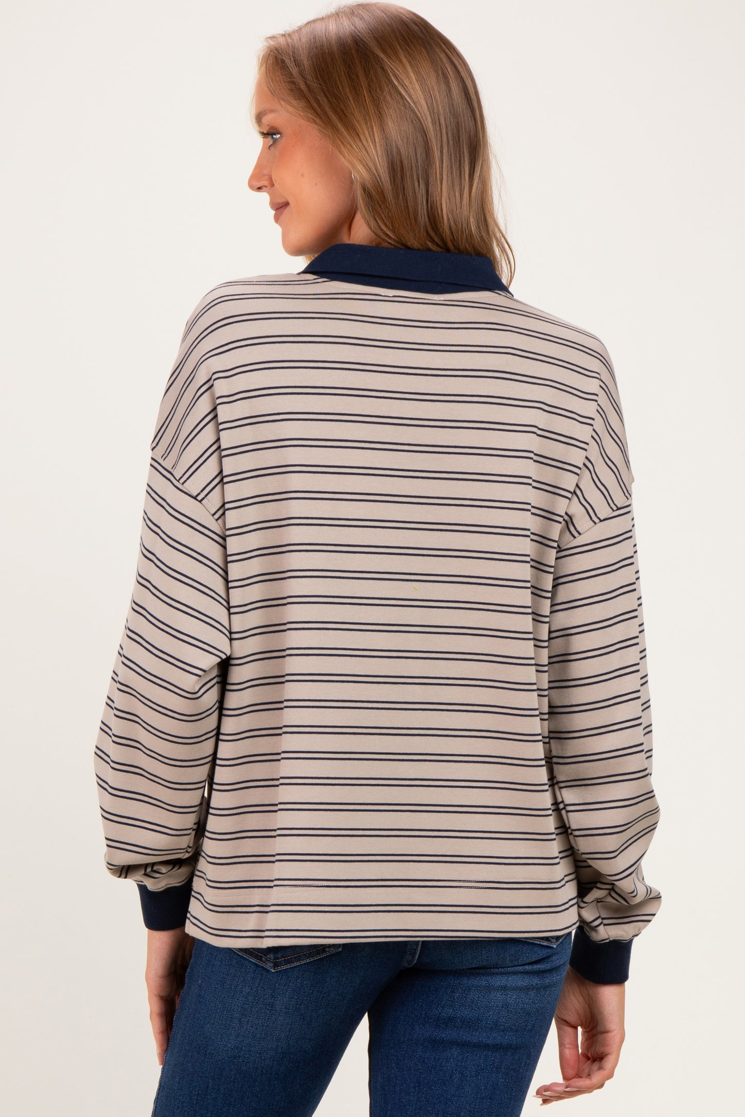 woman wearing a beige striped maternity top with navy accents and balloon sleeves, view from the back