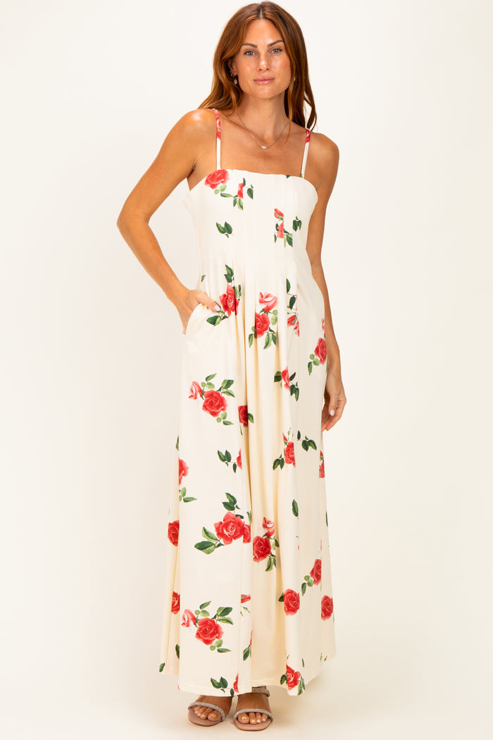 woman wearing a white maxi dress with red rose prints and pockets, featuring thin straps and a fitted bodice