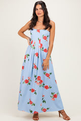woman wearing a light blue floral maxi dress with red roses, styled with strappy heels