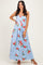 woman wearing a light blue floral maxi dress with red roses, styled with strappy heels