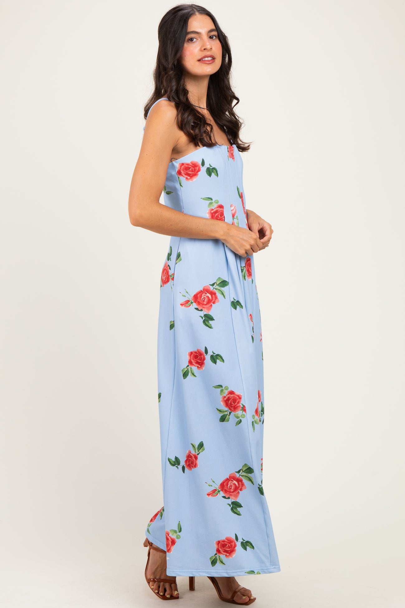 woman wearing a light blue sleeveless maxi dress with a floral rose print