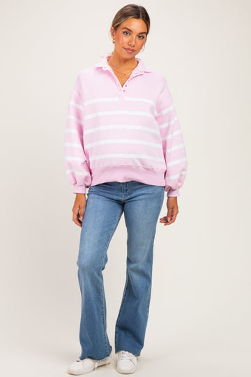 woman wearing a pink and white striped maternity pullover sweatshirt with a collar, paired with light blue flared jeans