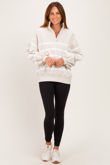 woman wearing a beige striped oversized sweatshirt with a collar and black leggings