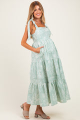 woman wearing a green and white striped maternity dress with tie straps and a flowing skirt, showcasing a baby bump