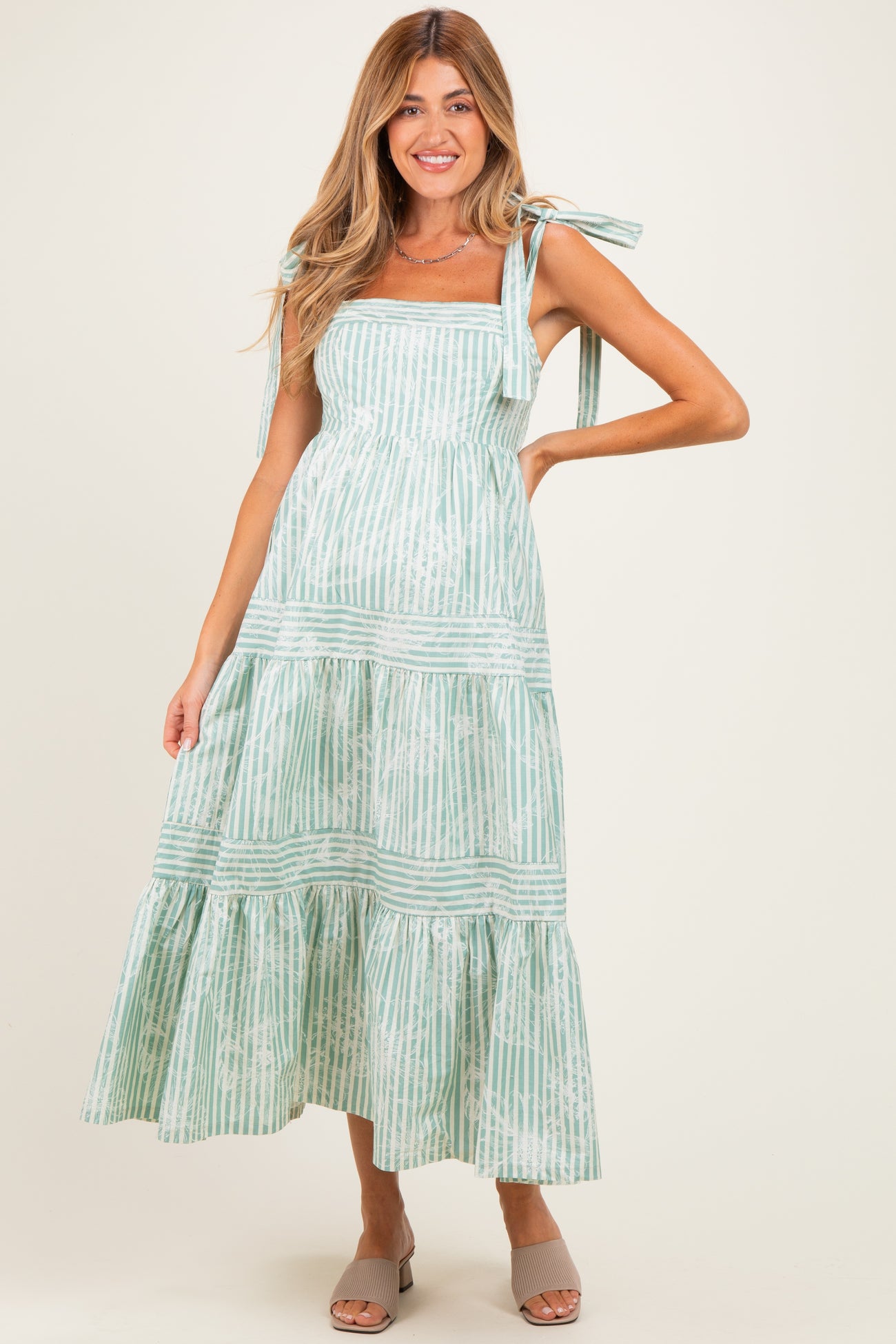 woman wearing a mint green striped maternity maxi dress with tie shoulder straps and tiered skirt