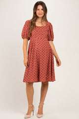 woman wearing a rust-colored maternity dress with black polka dots and puff sleeves