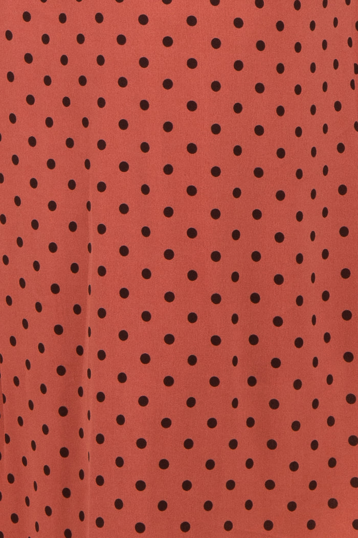 rust polka dot fabric with black spots, suitable for various clothing styles