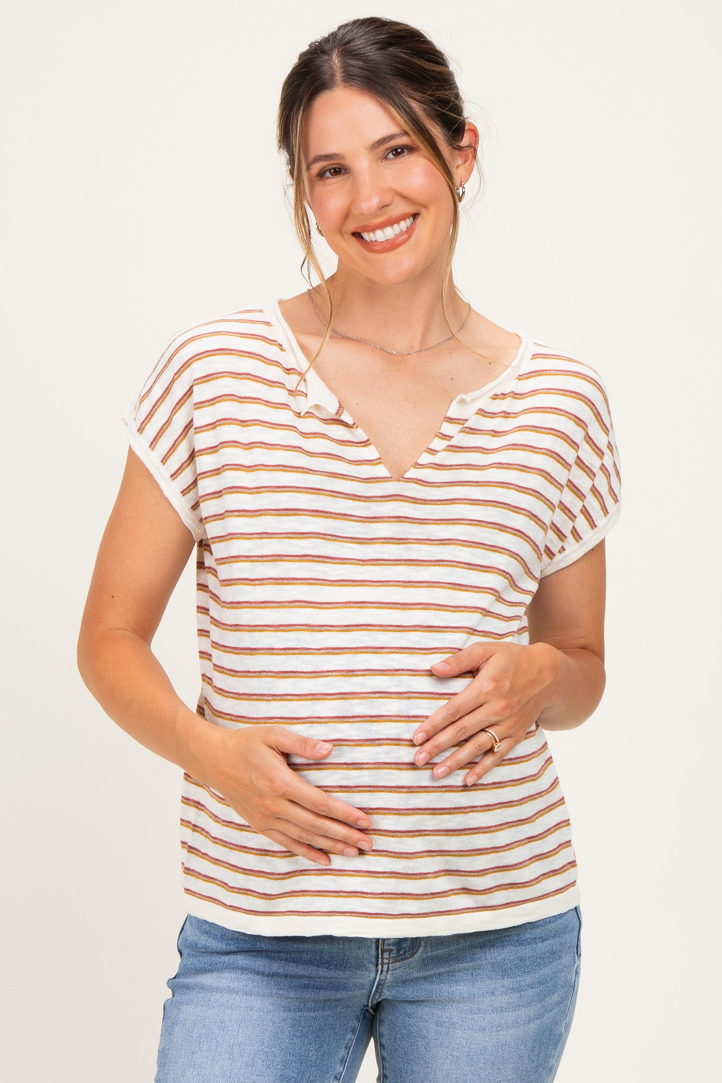 woman wearing a striped short sleeve maternity top and gently holding her baby bump