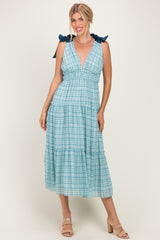 woman wearing a blue plaid midi dress with tie straps and a tiered skirt