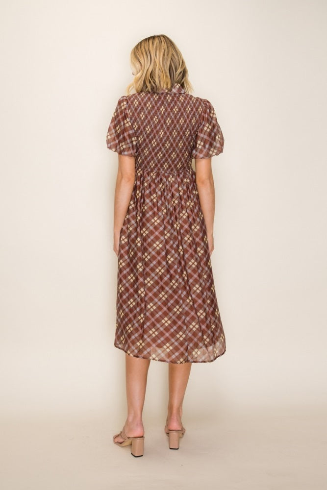 woman wearing a brown plaid midi dress with puff sleeves, showing the back view
