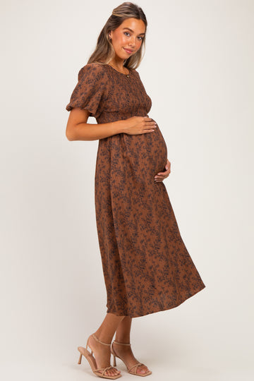 woman wearing a brown floral print maternity dress and holding her baby bump