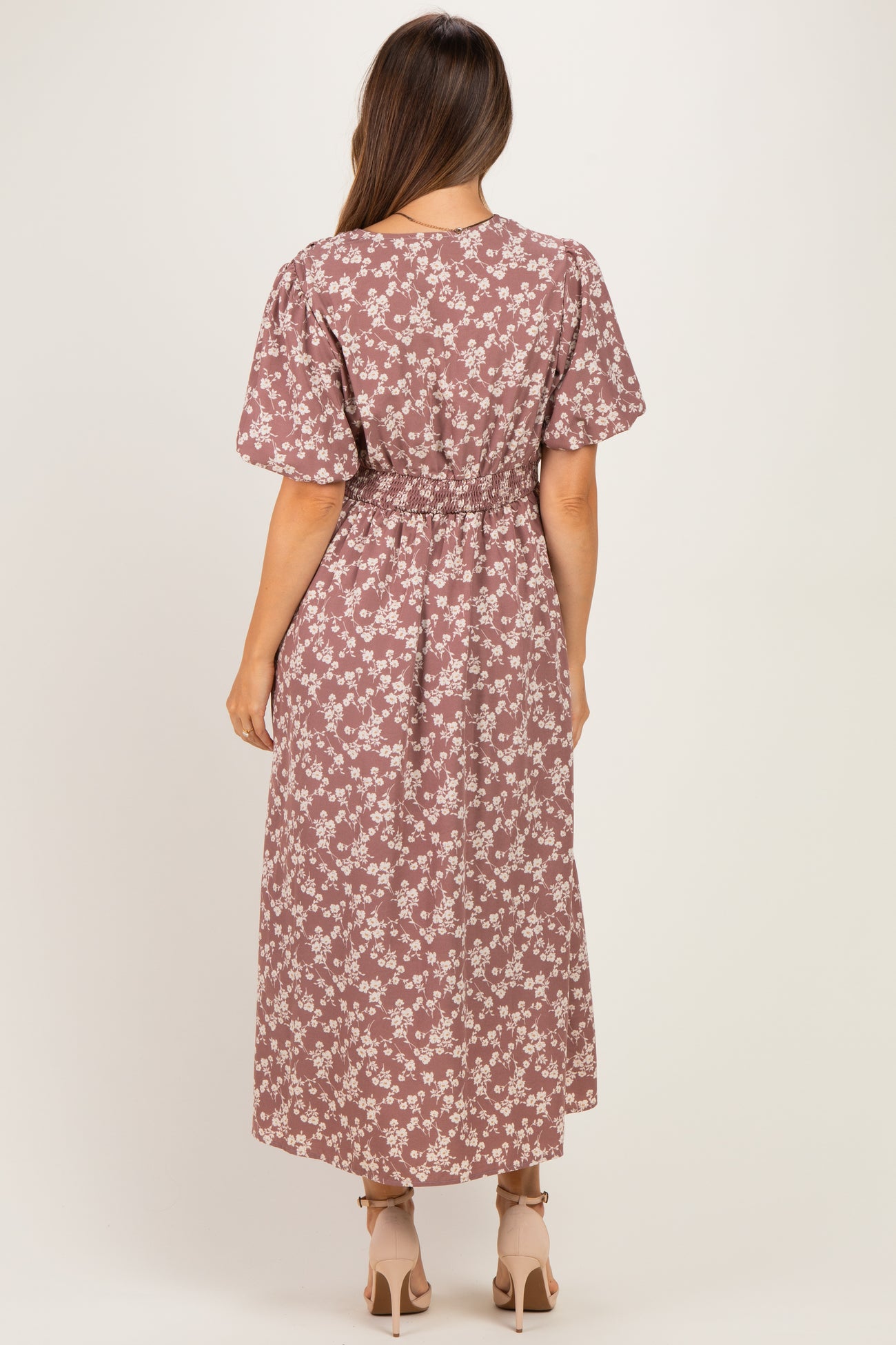 woman wearing a floral print brown maternity maxi dress with a cinched waist, seen from the back