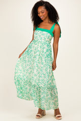 woman wearing a green and white floral maxi dress with tie-shoulder straps and a tiered bottom