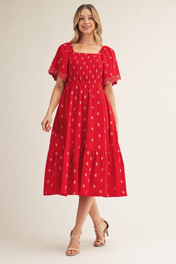woman wearing a red midi dress with puff sleeves and a tiered skirt displaying gold dot patterns