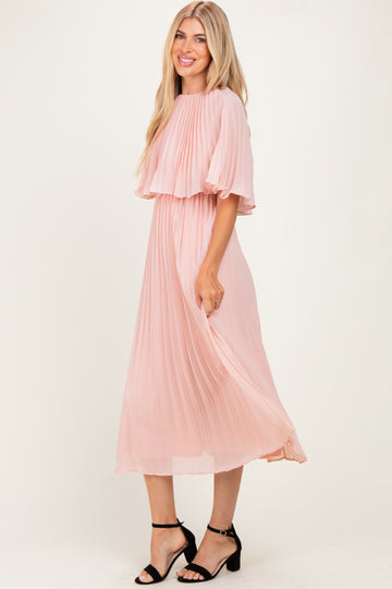 woman wearing a light pink pleated midi dress with flutter sleeves and a flowy silhouette