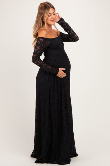 woman wearing a black off-the-shoulder lace maternity gown and cradling her baby bump