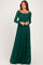 woman wearing a green lace long sleeve maxi maternity dress with a square neckline and flowing skirt
