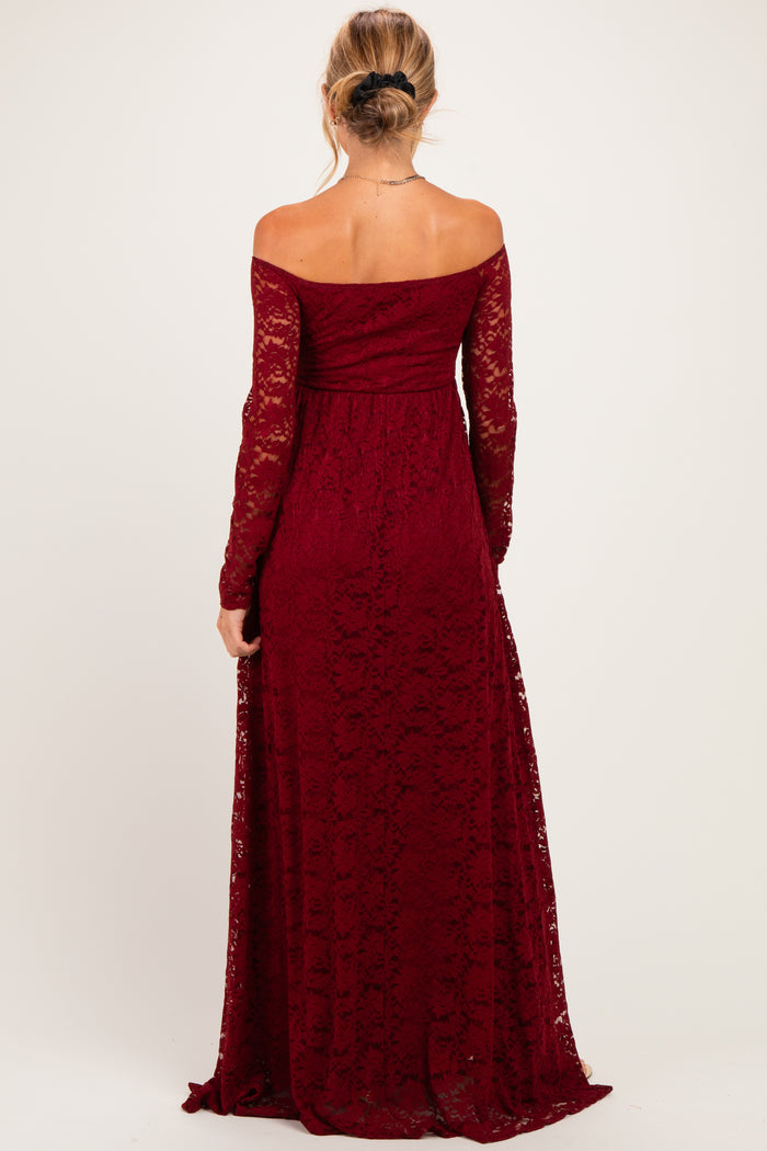 woman wearing a burgundy lace off-the-shoulder maternity dress with long sleeves and a flowing skirt, showing her back