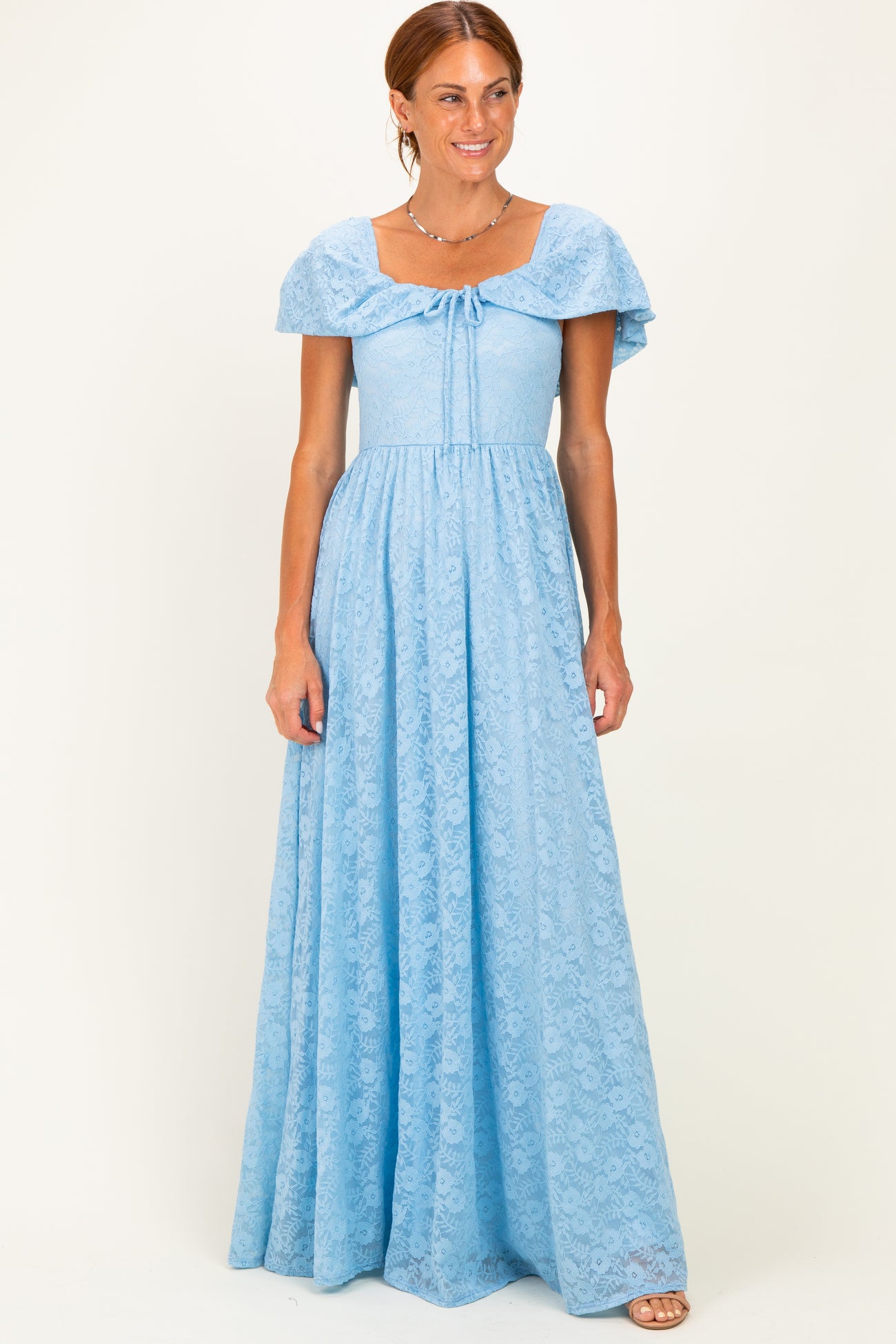 woman wearing a light blue maxi dress with short flutter sleeves and a tied neckline