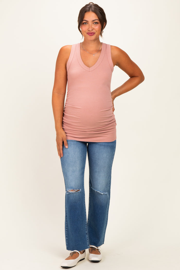 woman wearing a pink ribbed tank top with a v-neck and revealing a baby bump, paired with distressed blue jeans