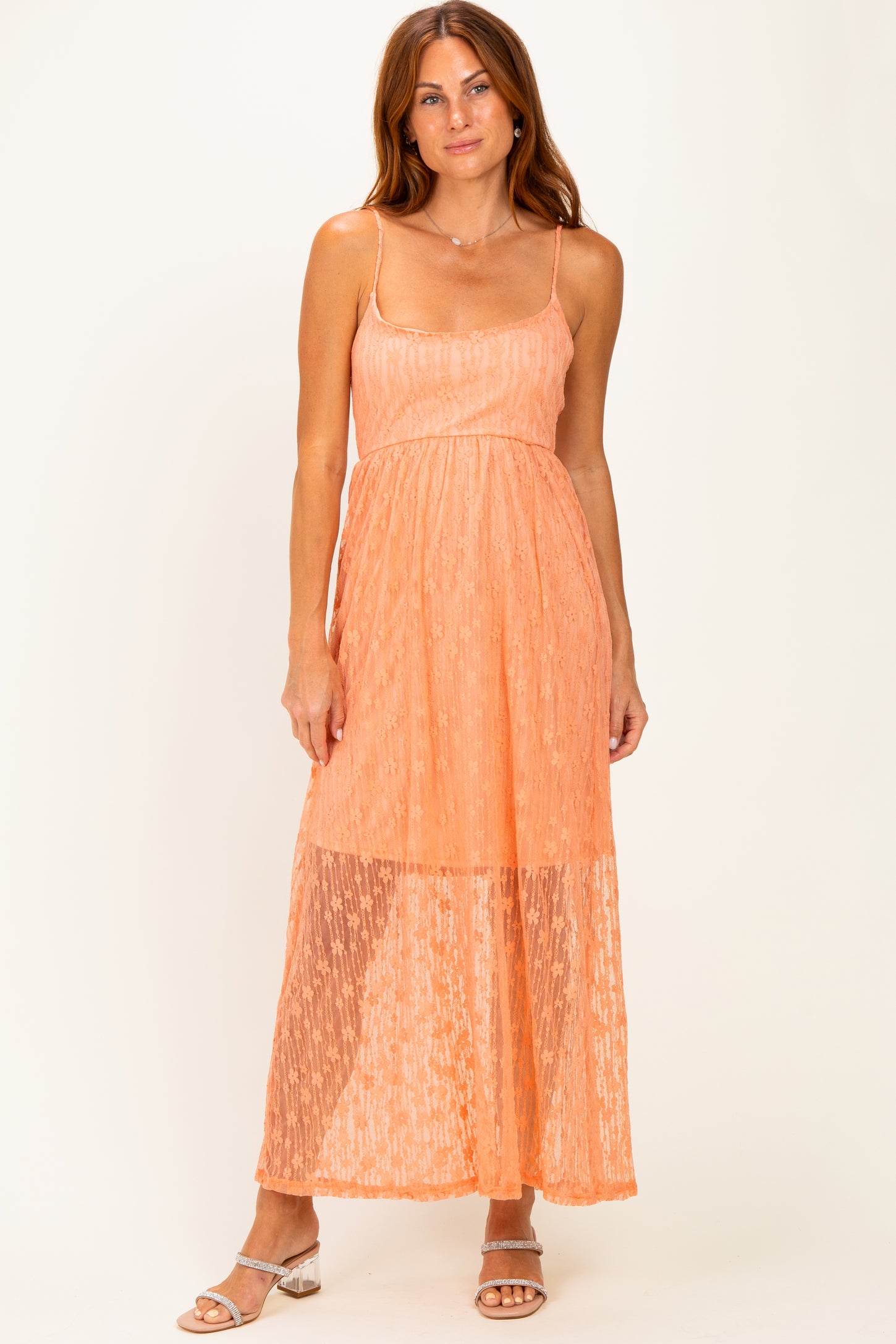 woman wearing a peach spaghetti strap maxi dress with a textured design and sheer lower hemline