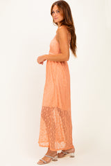 woman wearing an orange lace maxi dress with a fitted bodice and flowing skirt, standing in profile