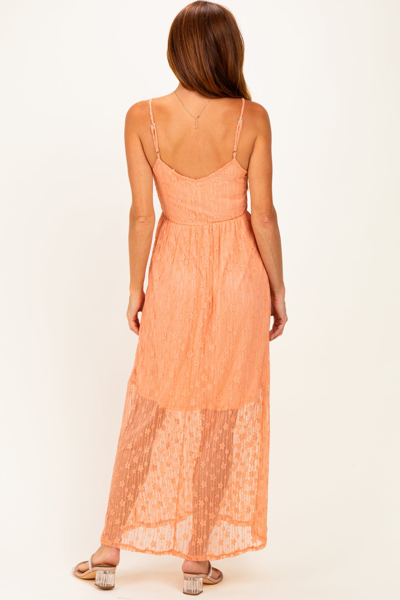 woman wearing a peach maxi dress with a sheer bottom and adjustable spaghetti straps, showing the back view