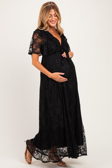 woman wearing a black lace maternity maxi dress and gently holding her baby bump