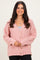 woman wearing a pink fluffy cardigan with buttons and a v-neckline, styled with a grey top underneath and black pants