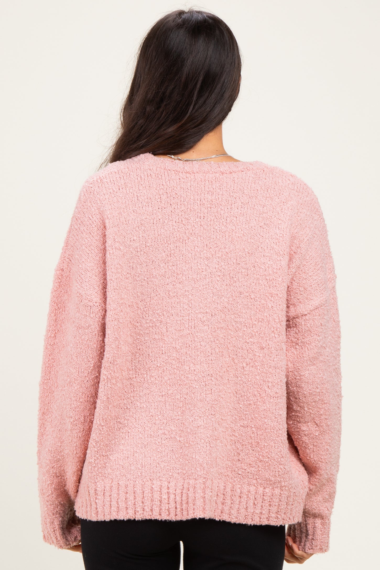 woman wearing a soft pink oversized sweater with a textured finish, viewed from the back
