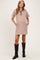 woman wearing a striped brown and cream maternity dress with a button placket and pockets, styled with black knee-high boots