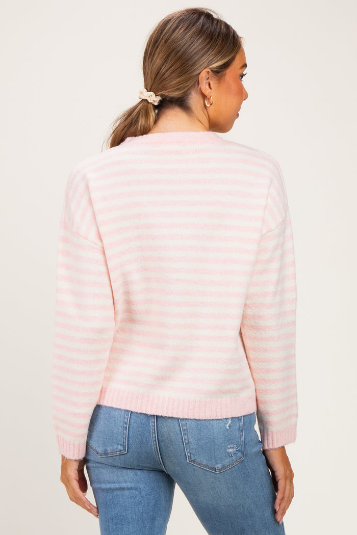 woman wearing a pink and white striped maternity sweater, showing her back, paired with blue jeans