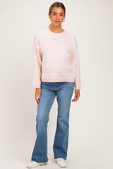 woman wearing a light pink striped maternity sweater and blue flared jeans, with a relaxed fit