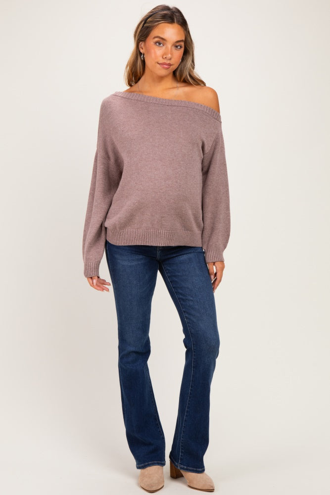 woman wearing a mauve off-the-shoulder maternity sweater with balloon sleeves and blue flared jeans