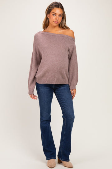woman wearing a mauve off-the-shoulder maternity sweater with balloon sleeves and blue flared jeans