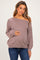 woman wearing a mauve off-the-shoulder maternity sweater and holding her baby bump