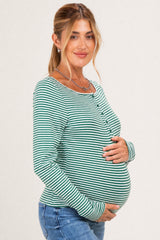 woman wearing a green and white striped long sleeve maternity top and holding her baby bump