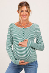 woman wearing a green and white striped maternity top with buttons, showcasing her baby bump