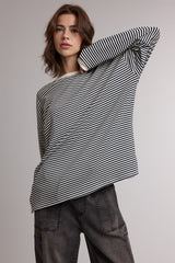 woman wearing a black and white striped oversized long sleeve top with a relaxed fit and dark gray trousers
