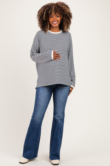 woman wearing a navy and white striped maternity sweatshirt and blue flared jeans, showing her baby bump