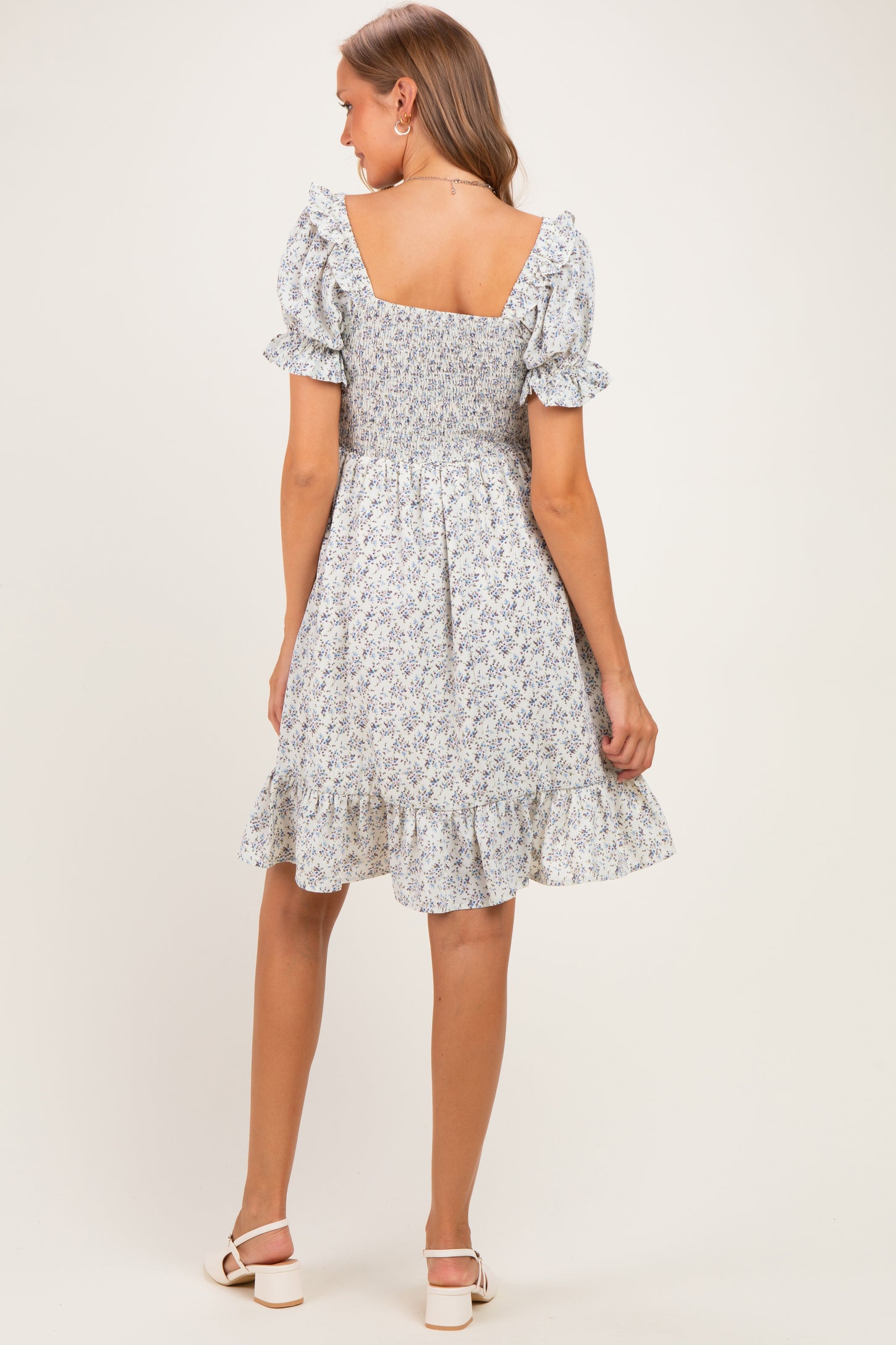 woman wearing a floral print maternity dress with short puff sleeves and a ruffled hem, showing a baby bump