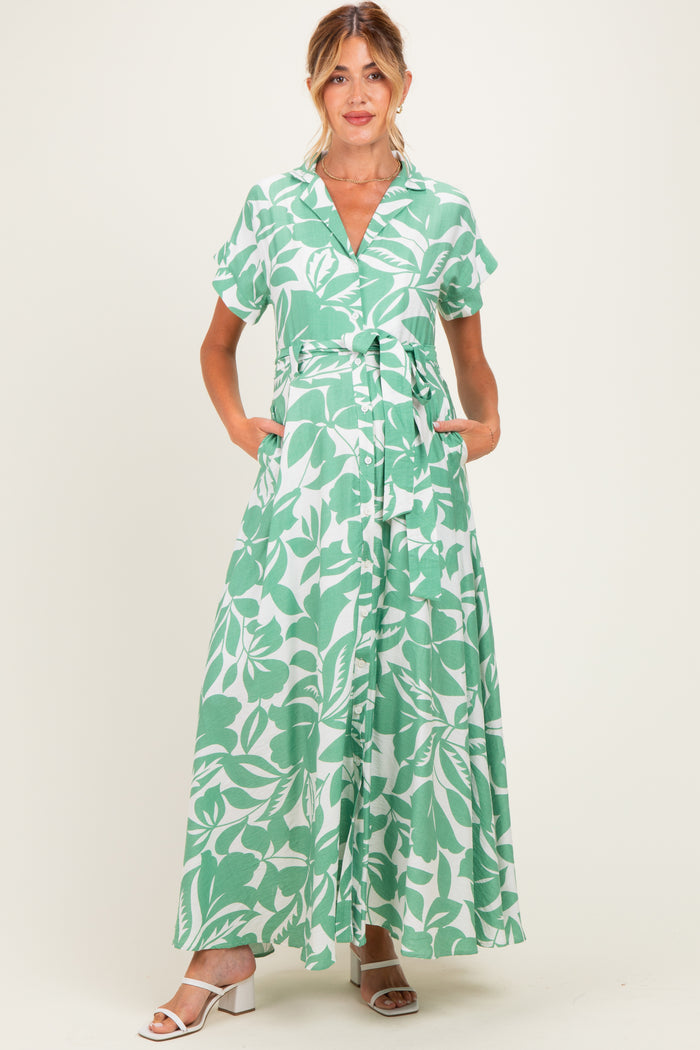 woman wearing a green and white floral maternity maxi dress with short sleeves and a tie waist, pockets visible