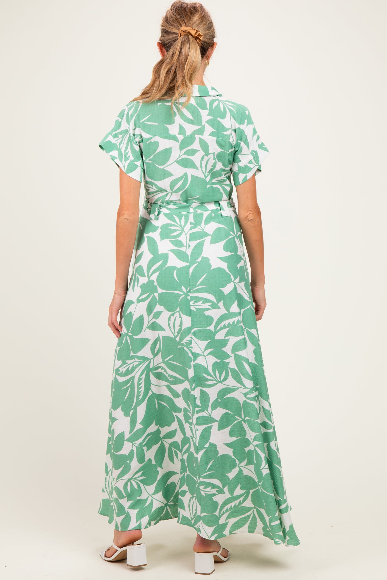 woman wearing a green floral maxi dress with short sleeves and a tie waist, viewed from the back