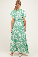 woman wearing a green floral maxi dress with short sleeves and a tie waist, viewed from the back