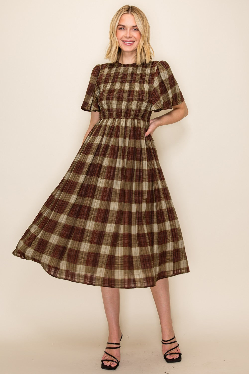 woman wearing a brown and beige plaid midi dress with short sleeves and a smocked bodice
