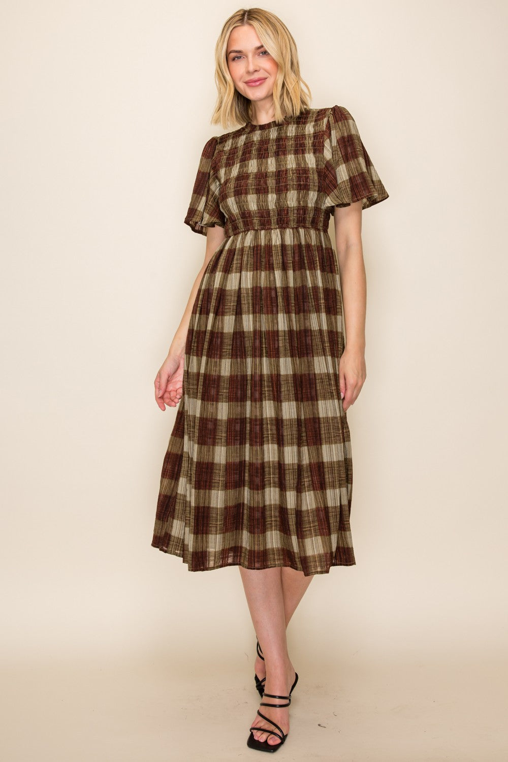 woman wearing a brown and beige plaid midi dress with short ruffle sleeves and smocked bodice
