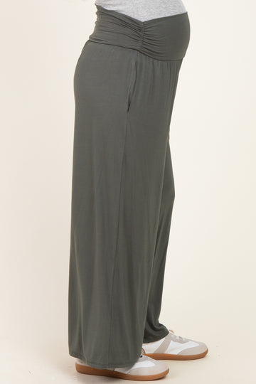 woman wearing a pair of dark green maternity wide-leg pants with a gathered waistband and visible baby bump
