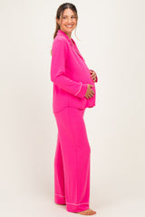woman wearing a bright pink long sleeve maternity pajama set and showcasing her baby bump